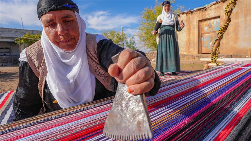 Evinin bahçesindeki tezgahta asırlık yöntemle kilim dokuyor